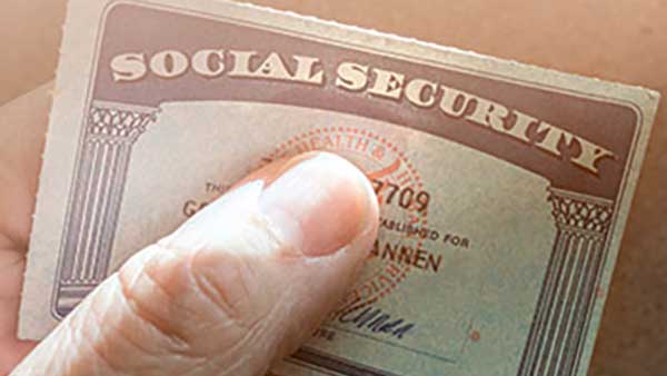 A person's thumb covering up part of the name and number on a Social Security card.
