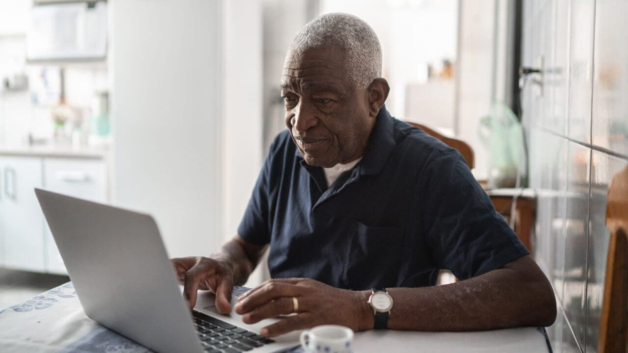 An older person using a laptop in their kitchen